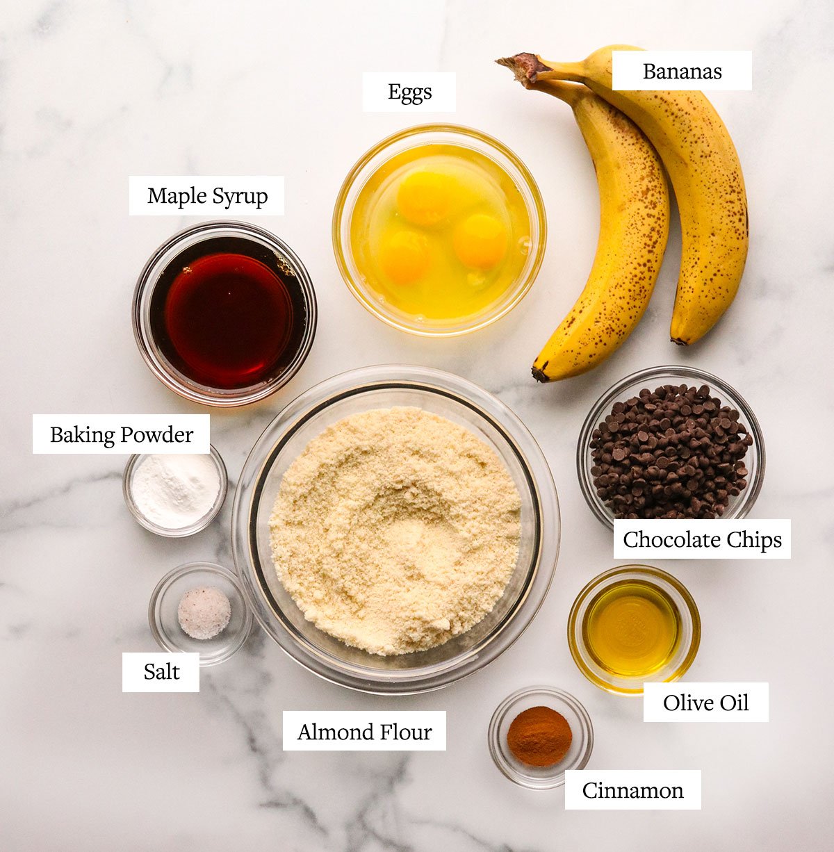 almond flour banana muffin ingredients labeled on a marble surface.