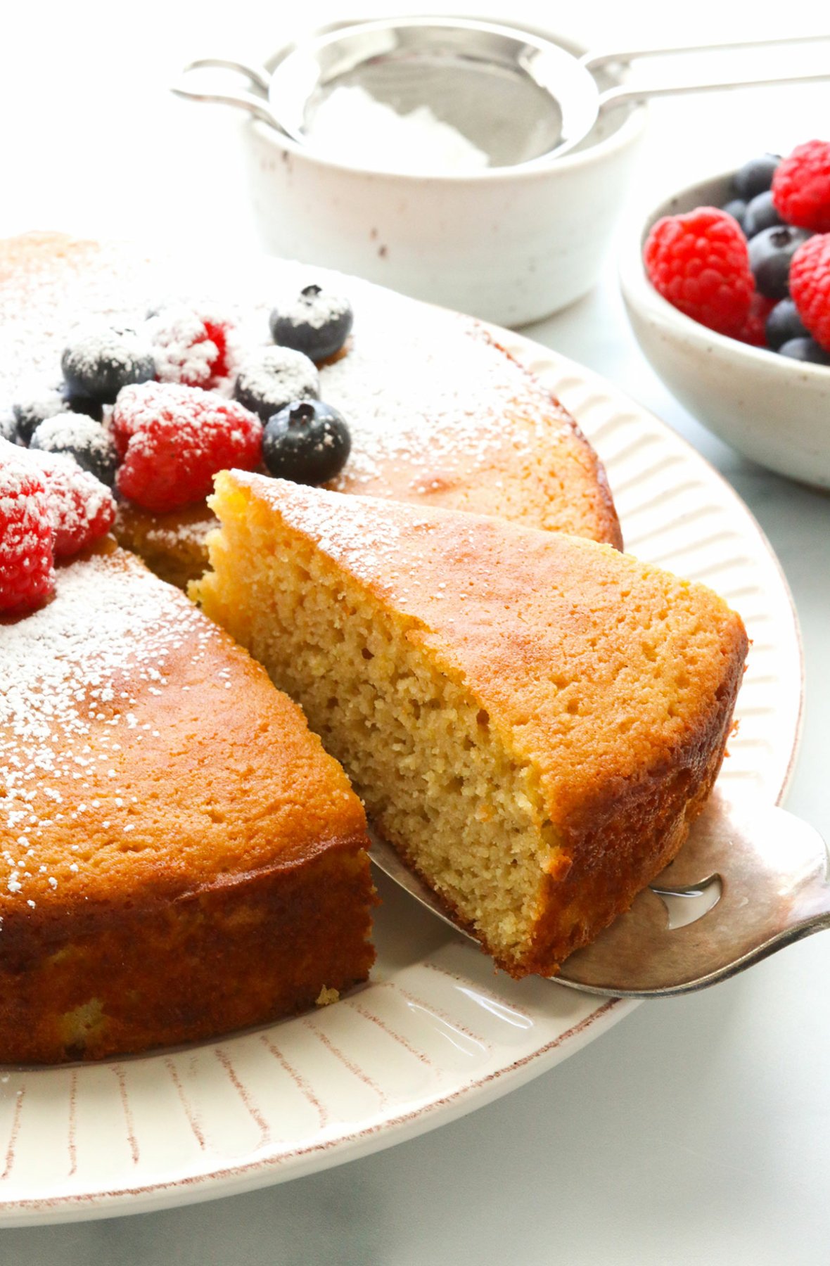 Almond flour cake topped with berries sliced and lifted on server. 