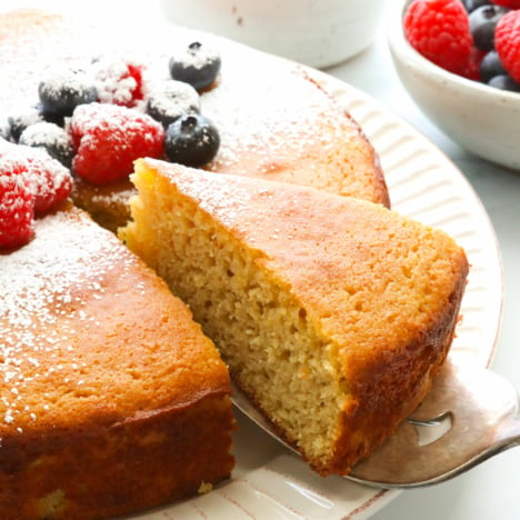 Almond flour cake topped with berries sliced and lifted on server.