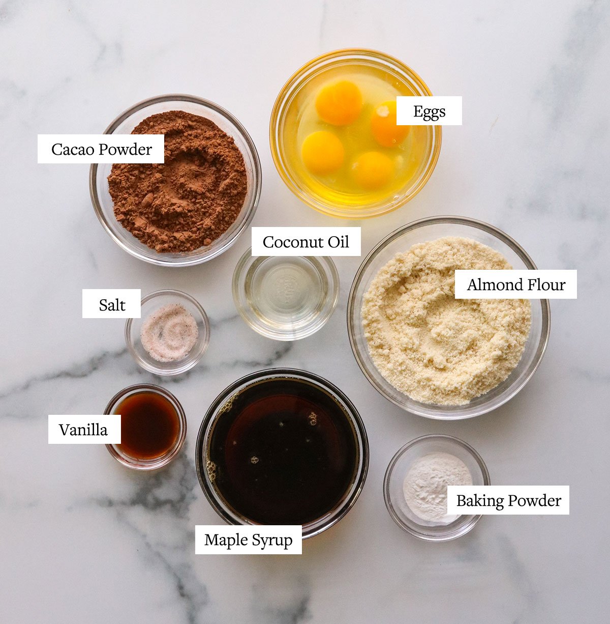 ingredients for chocolate almond flour cupcakes labeled on a white surface.