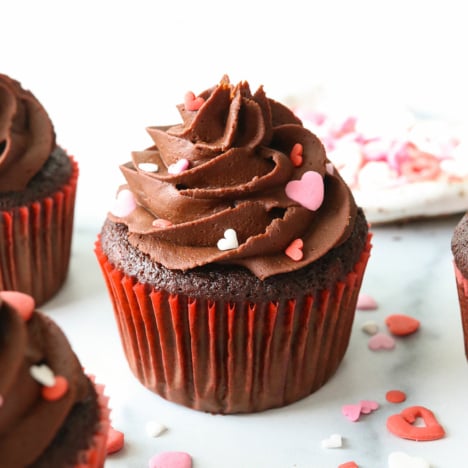 Chocolate almond flour cupcake topped with frosting and heart sprinkles.