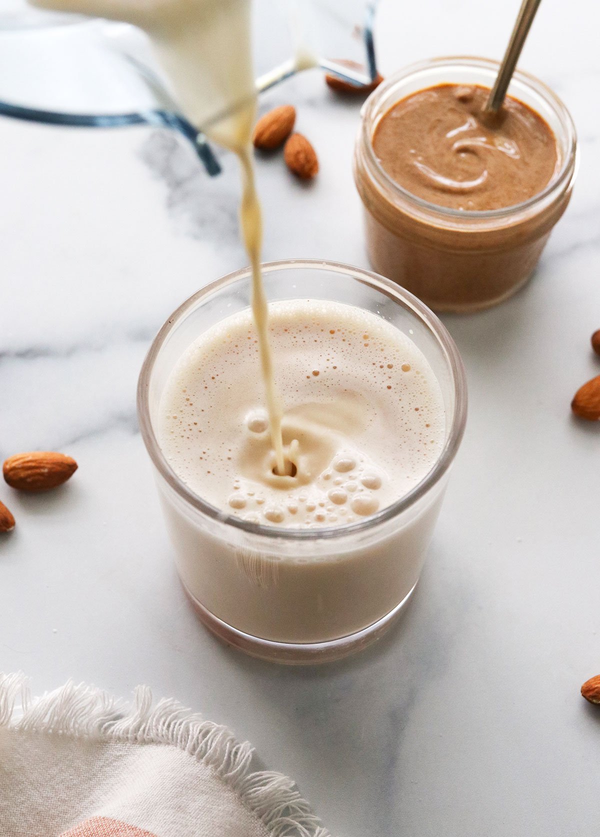 almond milk poured into a glass from a blender.