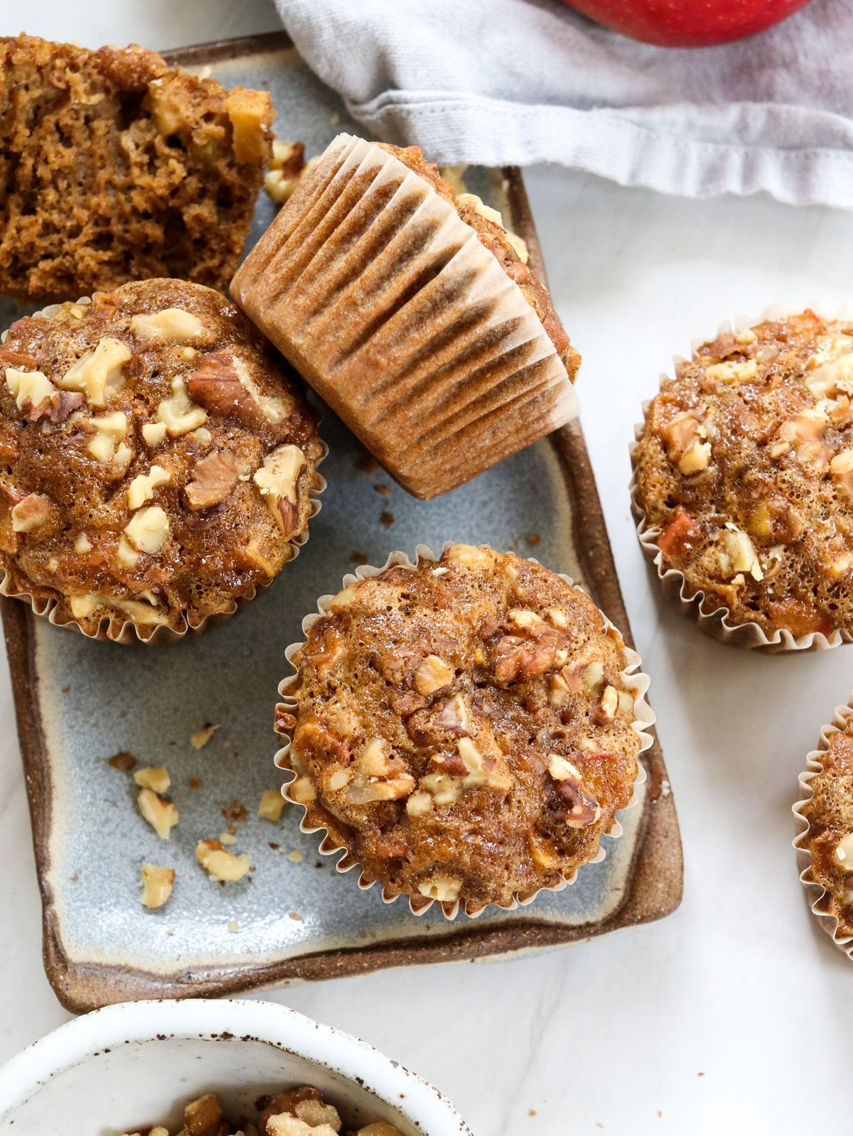 healthy apple muffins on blue plate with crushed walnuts.