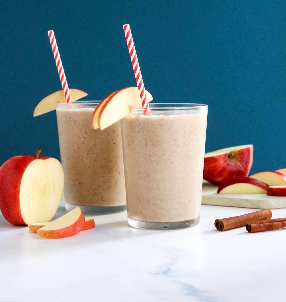 two glasses of apple smoothie with blue background