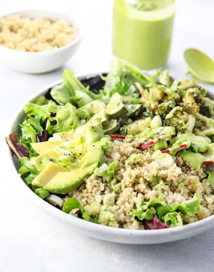 Summer salad topped with quinoa and avocado cilantro dressing