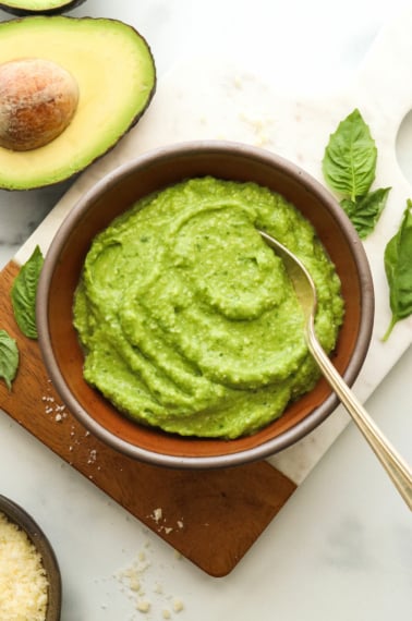 avocado pesto in a brown bowl with a spoon.