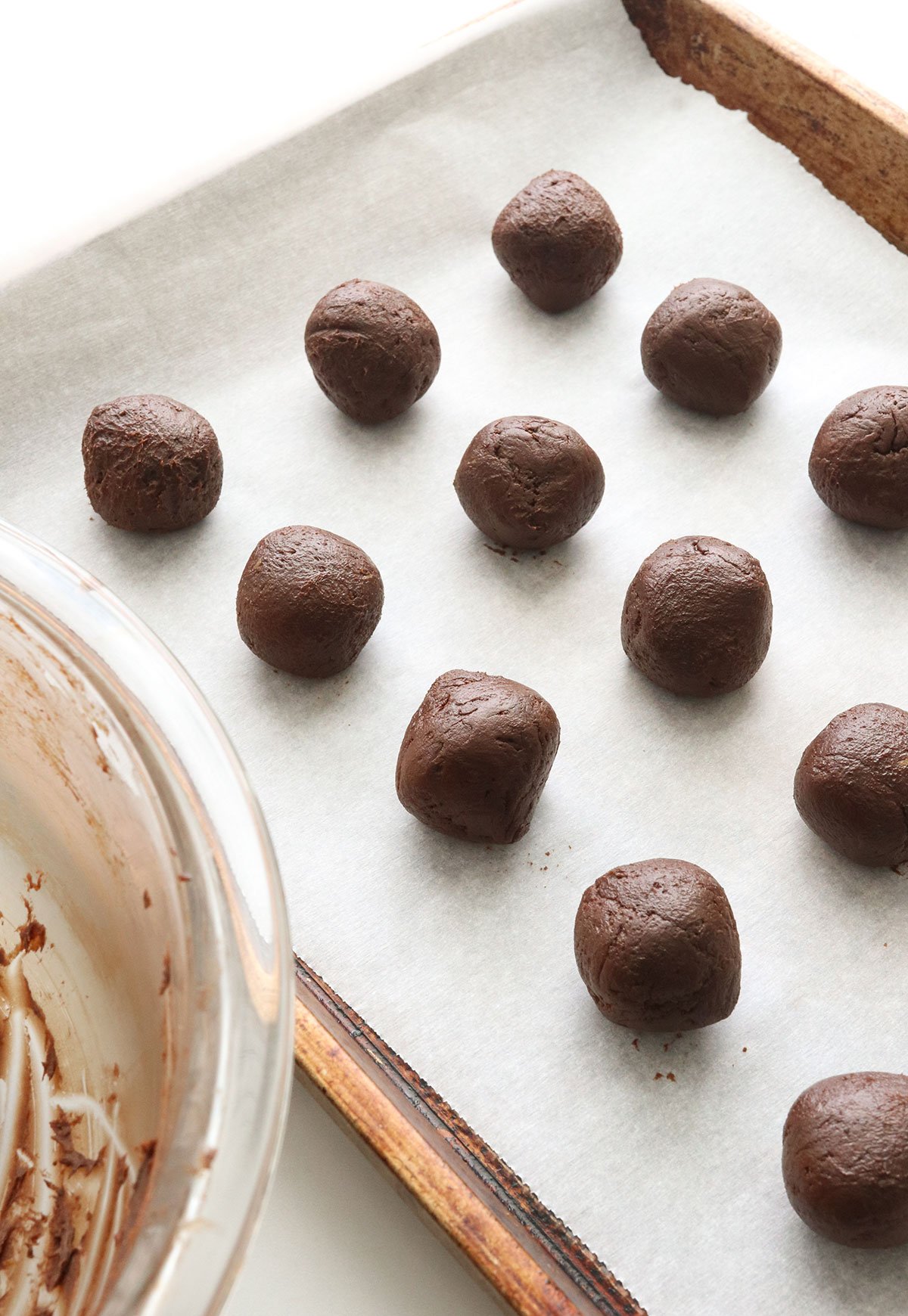 avocado truffles rolled into balls and arranged on a baking sheet.