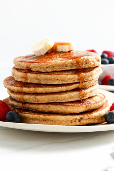 banana oatmeal pancakes stacked with maple syrup on top.