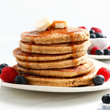 banana oatmeal pancakes stacked with maple syrup on top.