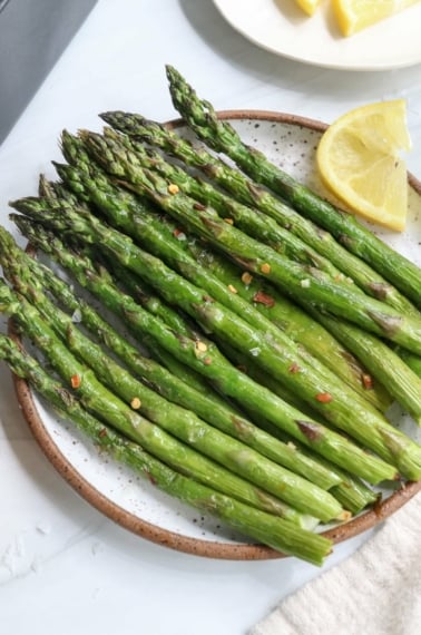 air fryer asparagus served on white plate with lemon.