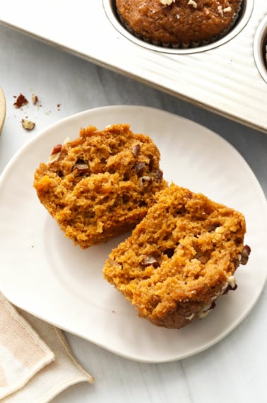 Sweet potato muffin split in half on a white plate.