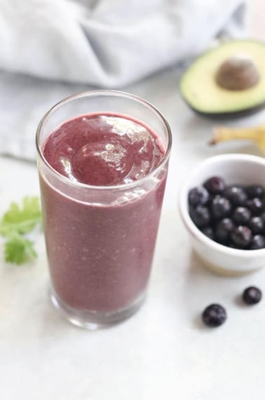 blueberry detox smoothie with bowl of frozen blueberries