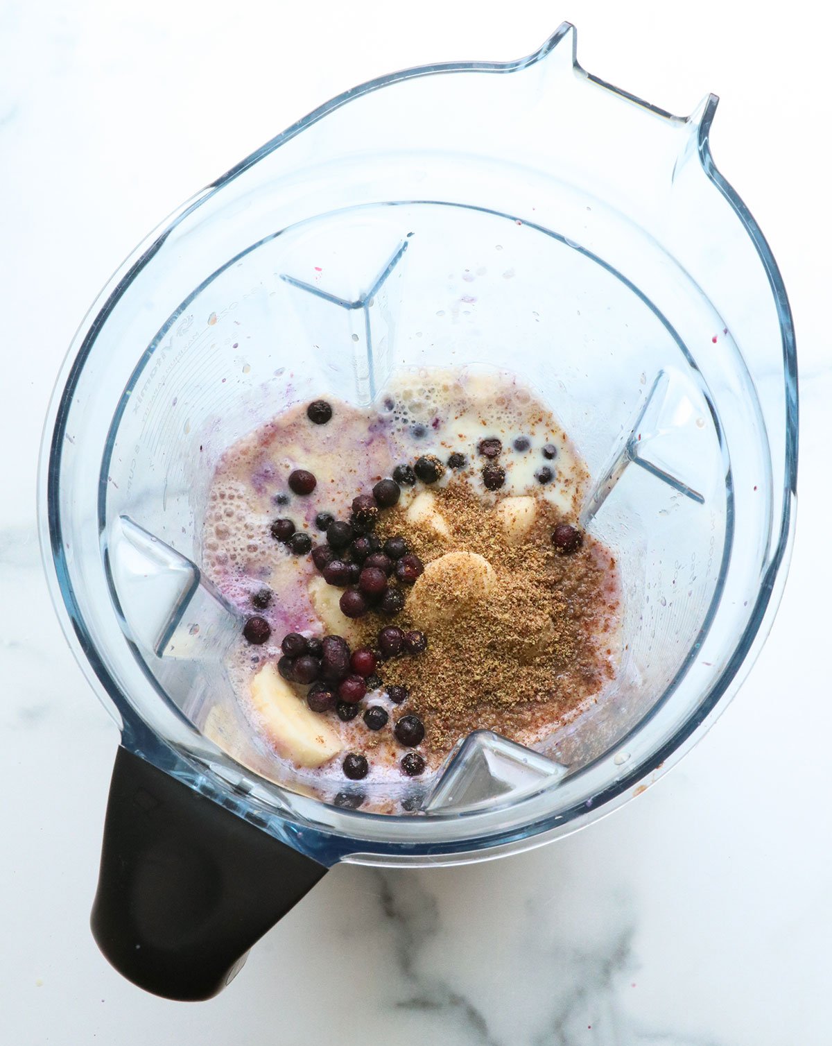 blueberries, bananas, and flax added to a blender with liquid.