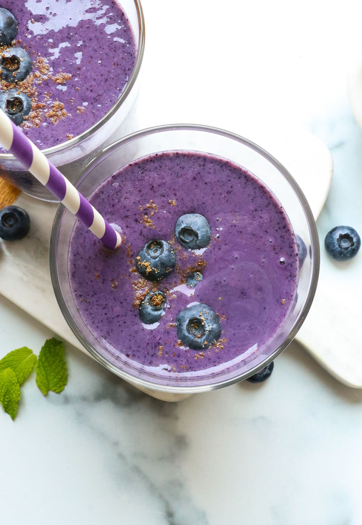 blueberry smoothie in two glasses with a straw.