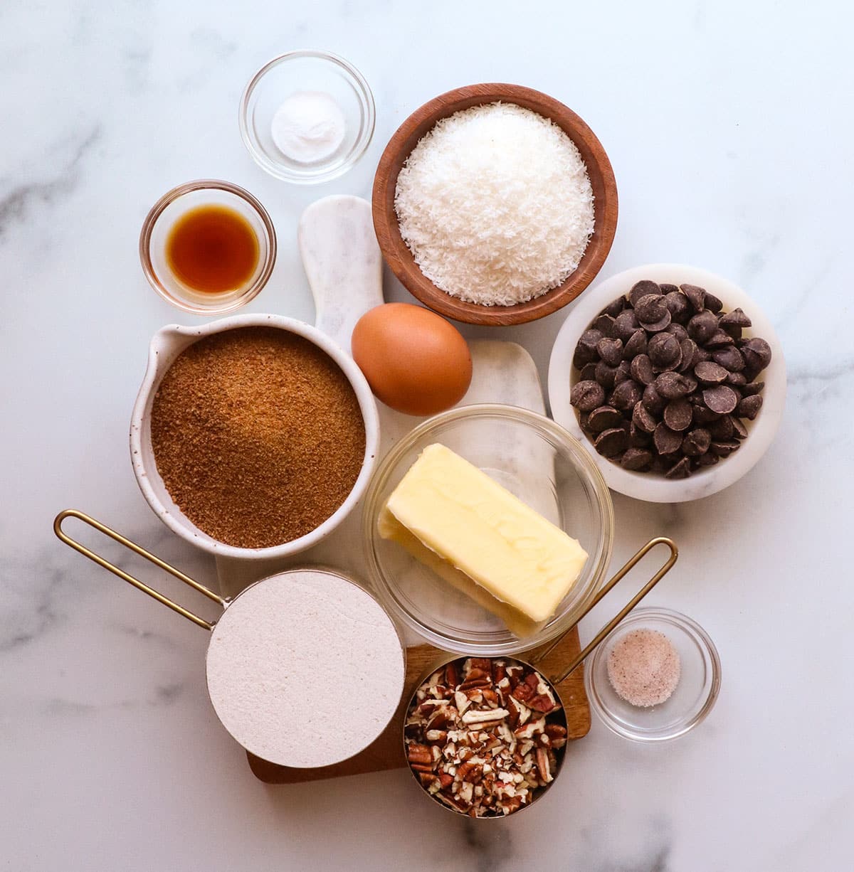 buckwheat flour, coconut sugar, coconut, chocolate chips, butter and more on white surface.