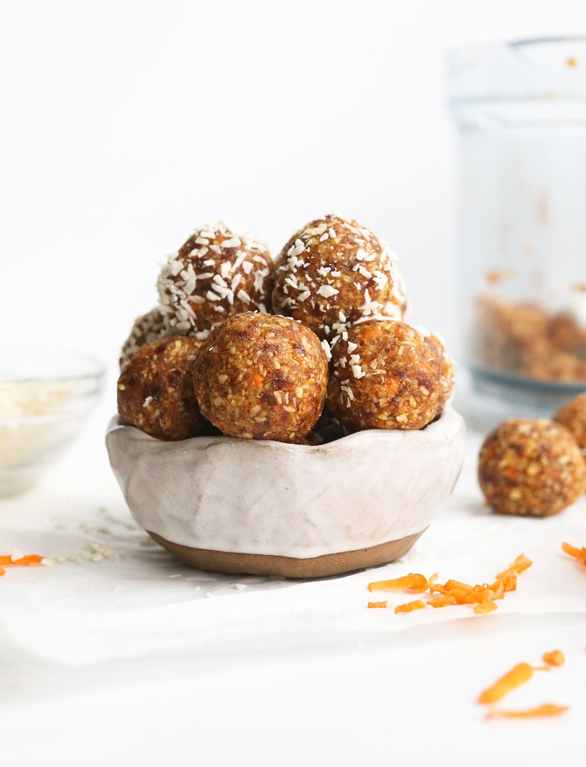 carrot cake bites stacked in a white bowl.