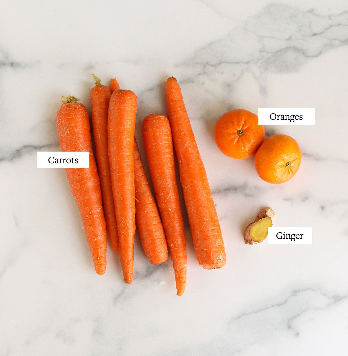 Carrot juice ingredients labeled on a marble board.