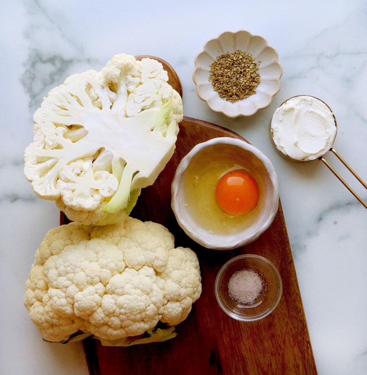 cauliflower pizza crust ingredients on a cutting board.