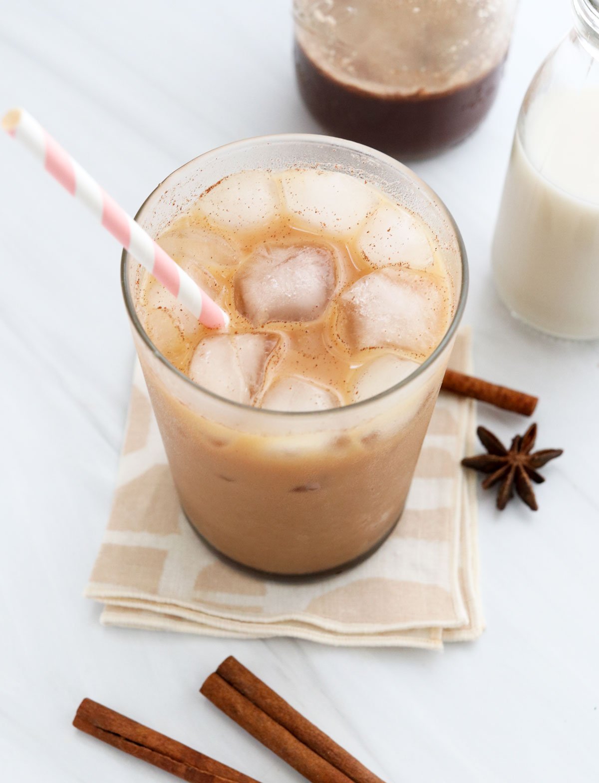 iced chai latte in glass with a pink straw.