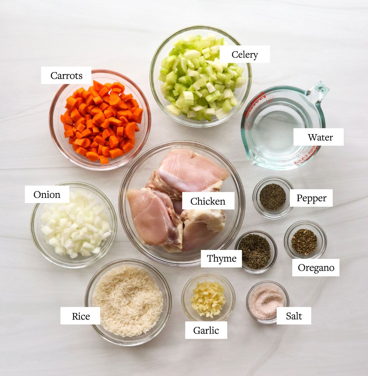 chicken and rice soup ingredients labeled in glass bowls.