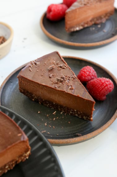 chocolate cheesecake slice on black plate with berries.