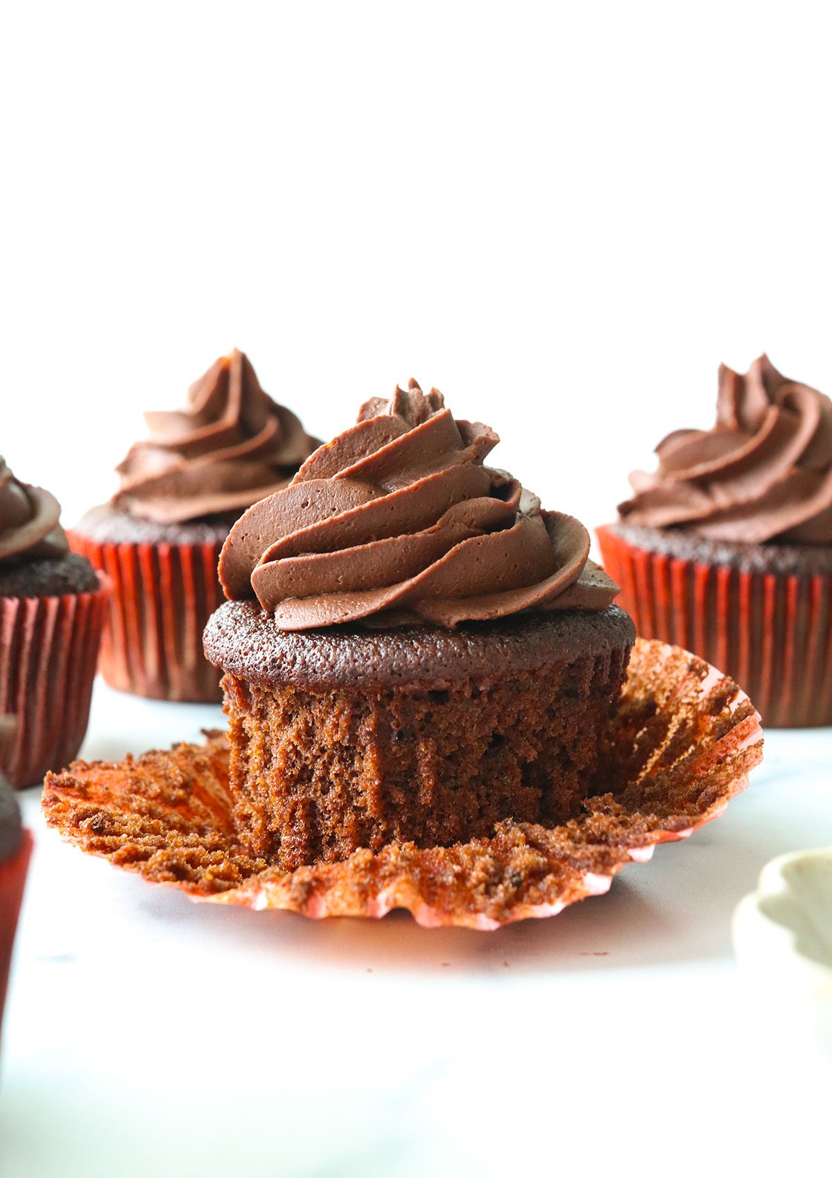 almond flour cupcake with wrapper peeled off and topped with frosting.