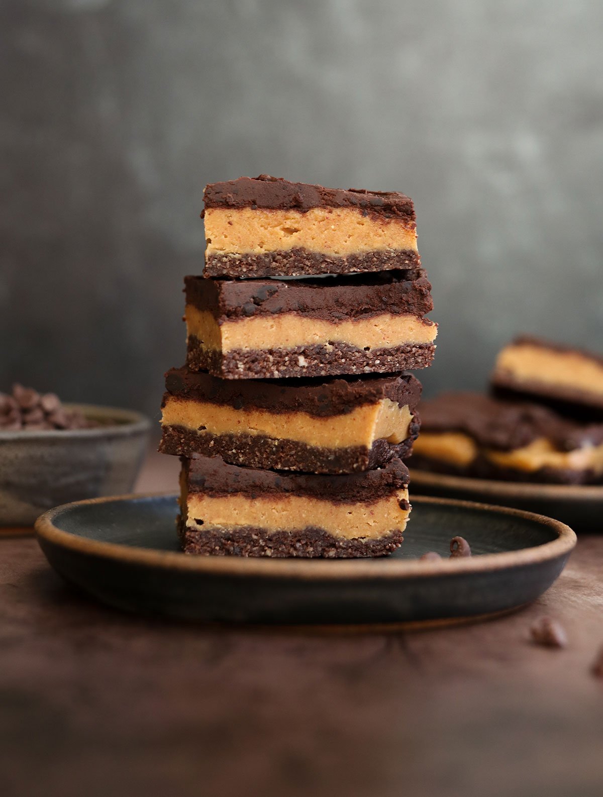 chocolate peanut butter bars stacked on dark plate.