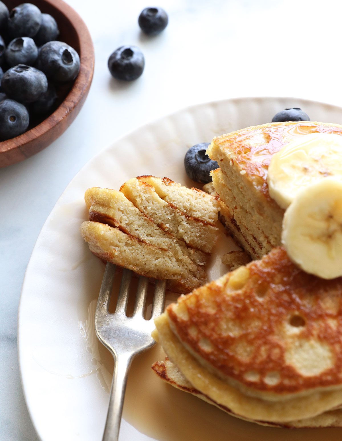 a fork full of coconut flour pancakes after cutting into a stack. 