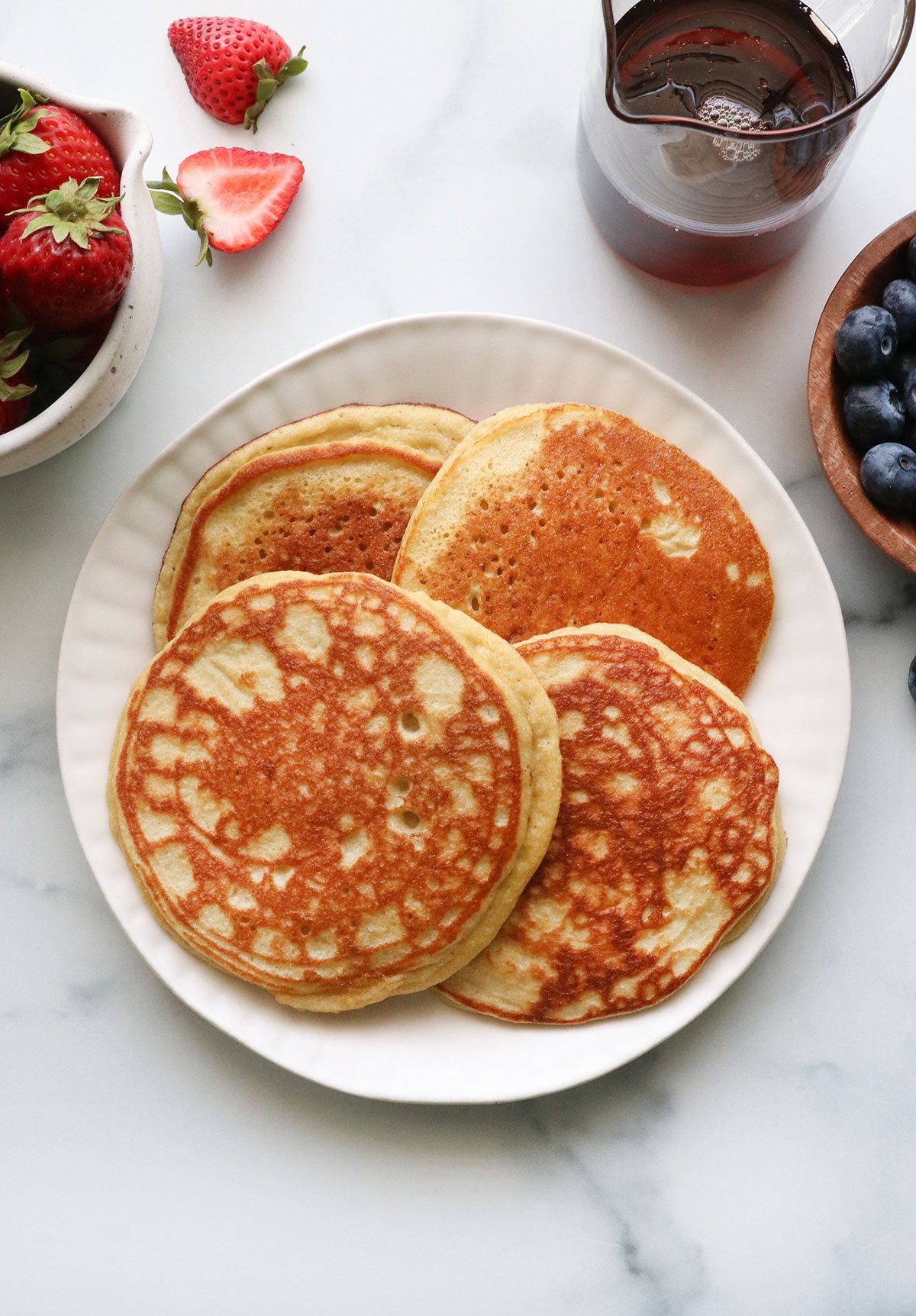 four coconut flour pancakes overhead on a white plate.