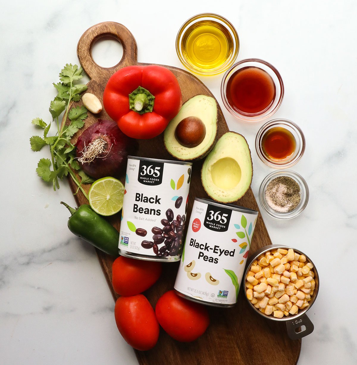 bell pepper, avocado, tomatoes, corn, cilantro, and avocado with canned beans on a board.