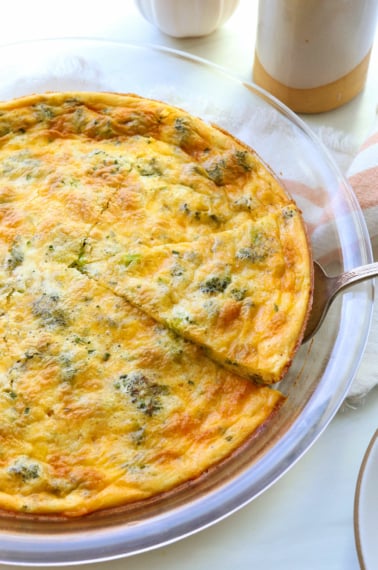 crustless quiche slice lifted out of a glass pie dish.