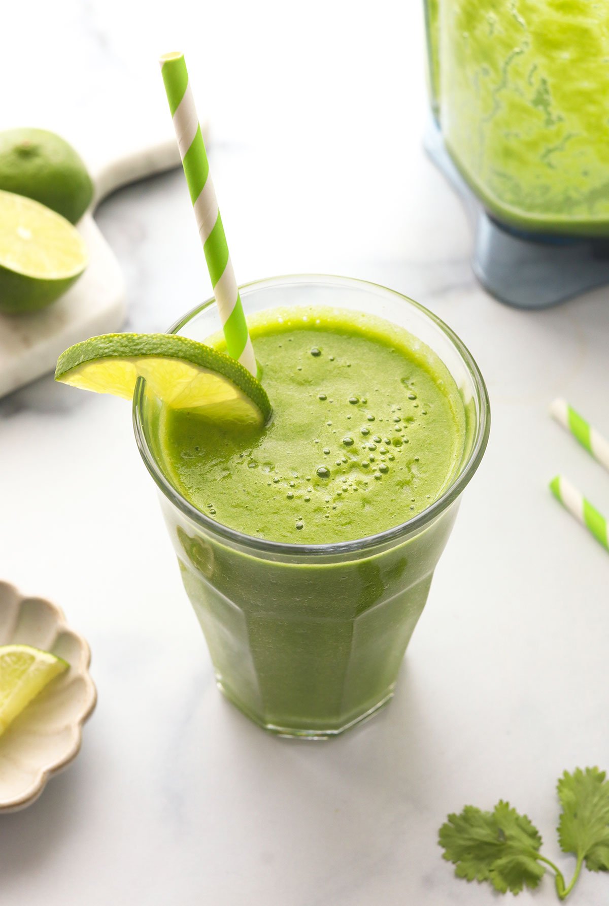 detox smoothie served in a glass with a lime slice and green paper straw.