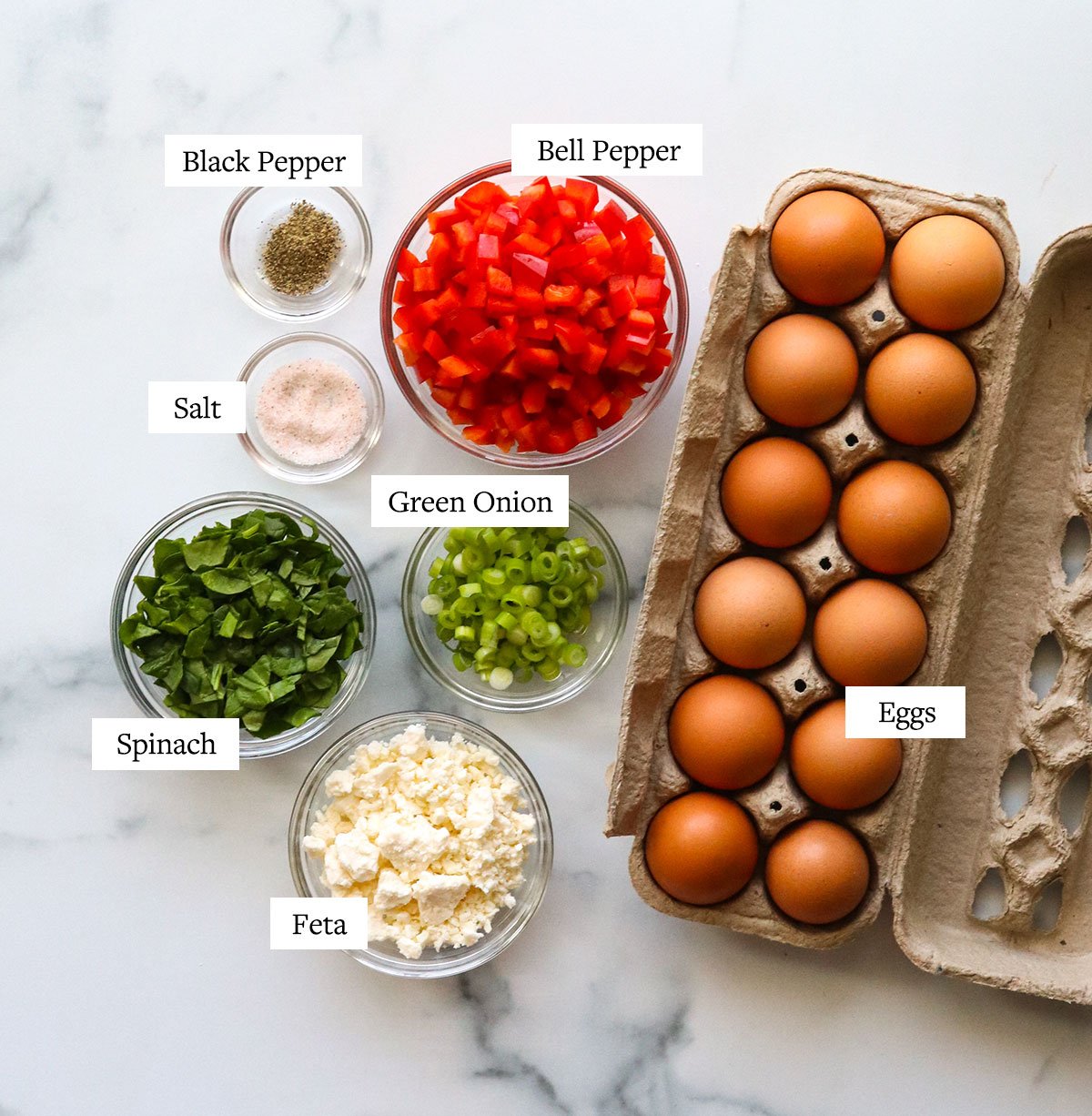 egg muffin ingredients labeled on a marble surface.