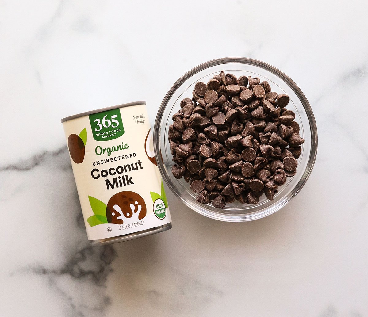 coconut milk and chocolate chips on a marble surface.