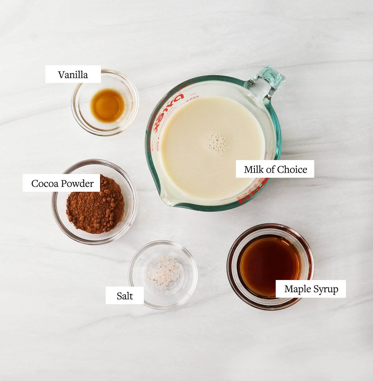 healthy hot chocolate ingredients labeled in glass bowls.