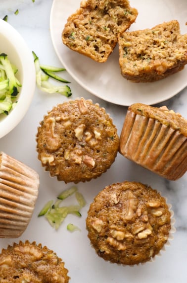 healthy zucchini muffins on a marble surface near shredded zucchini.