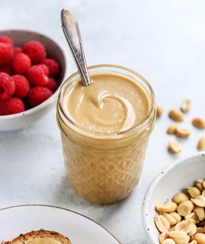 peanut butter in jar with raspberries behind