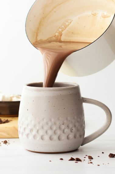 hot chocolate poured from a pan into a white mug.