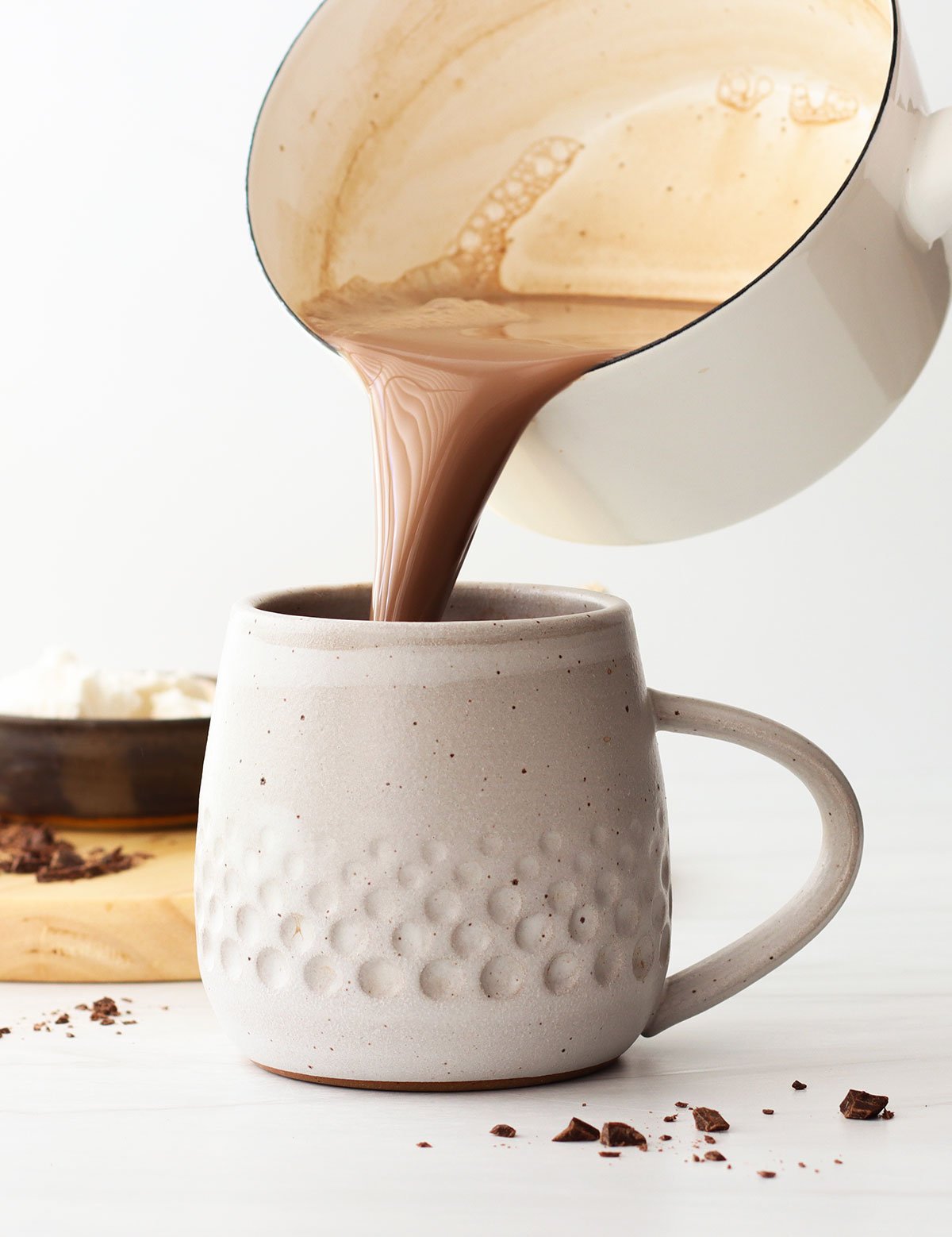 hot chocolate poured from a pan into a white mug.