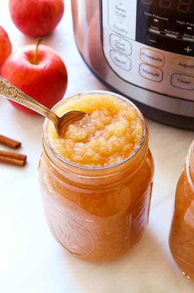 Instant Pot applesauce in two mason jars with a spoon.