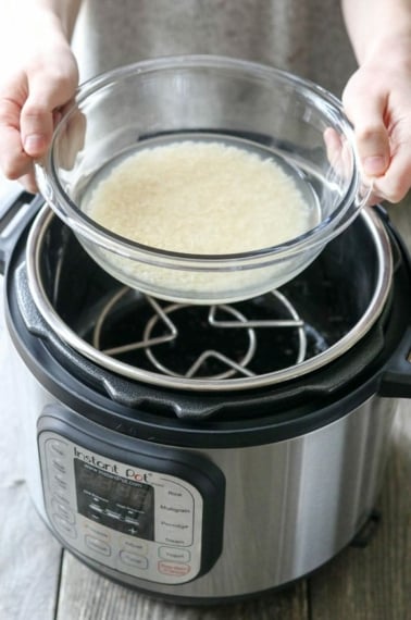 hands holding bowl of rice over Instant Pot