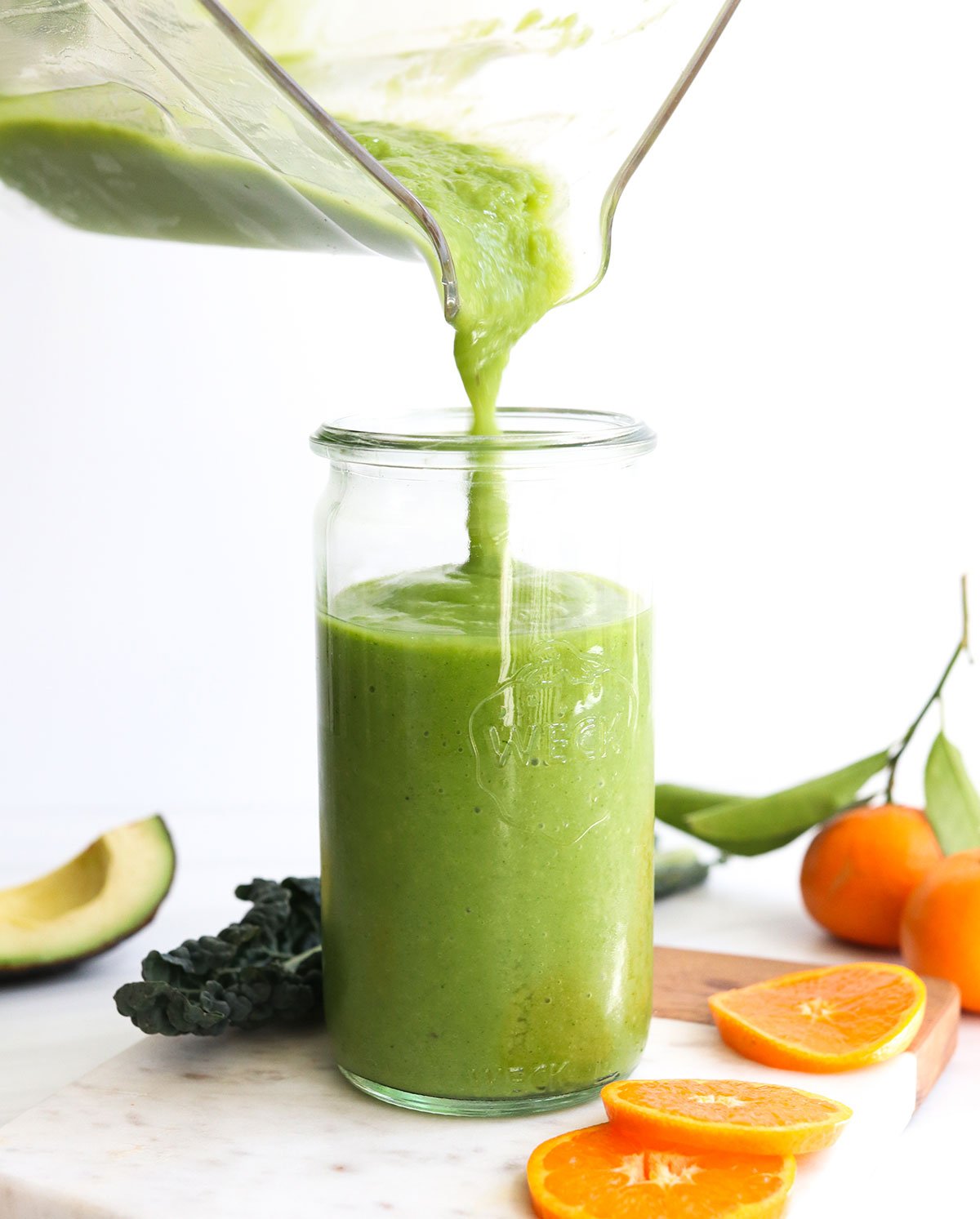 kale smoothie poured into a glass from the blender pitcher.