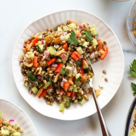 Lentil salad eaten with a fork on a white plate.