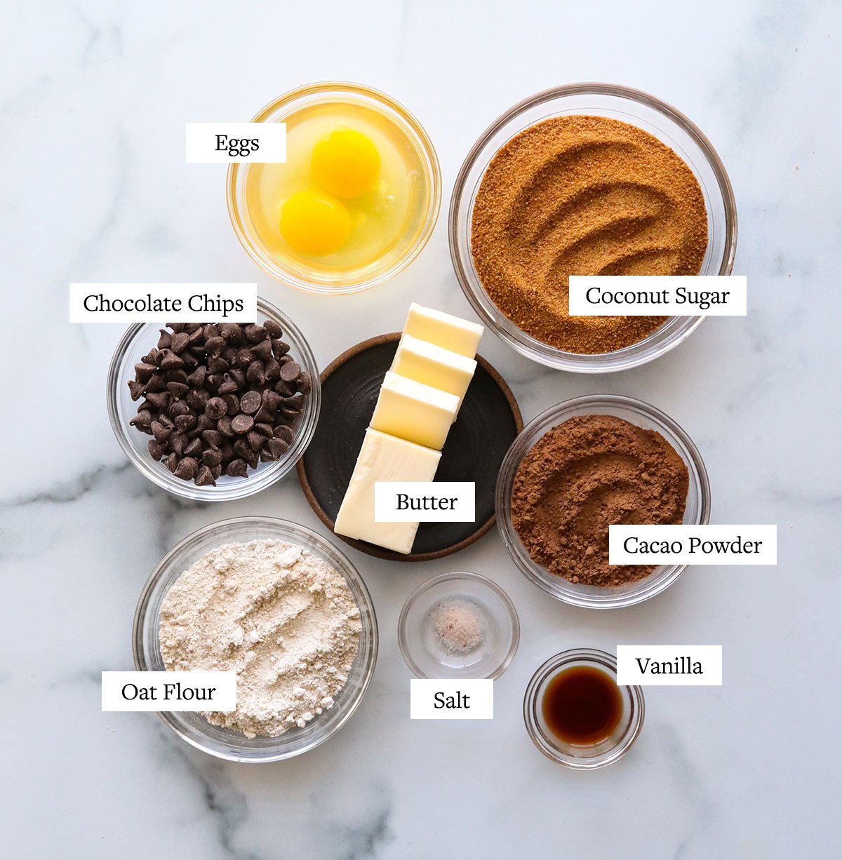 oat flour brownies ingredients labeled on a marble surface.