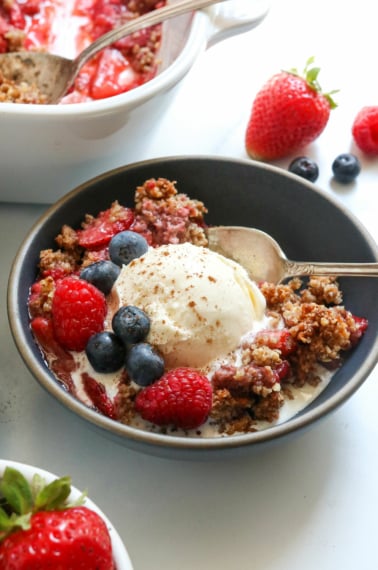 paleo berry crisp in dark bowl with ice cream