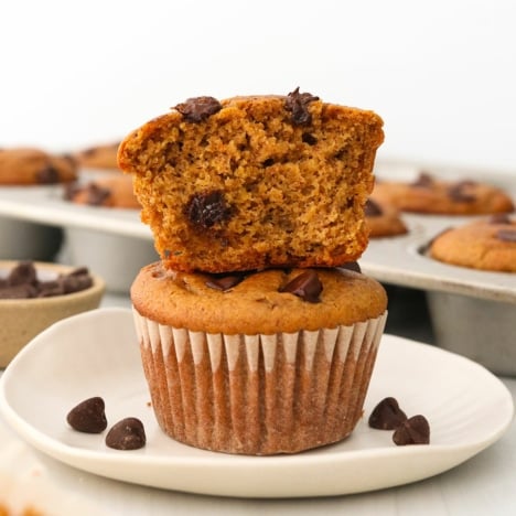 Paleo pumpkin muffins stacked on a white plate.