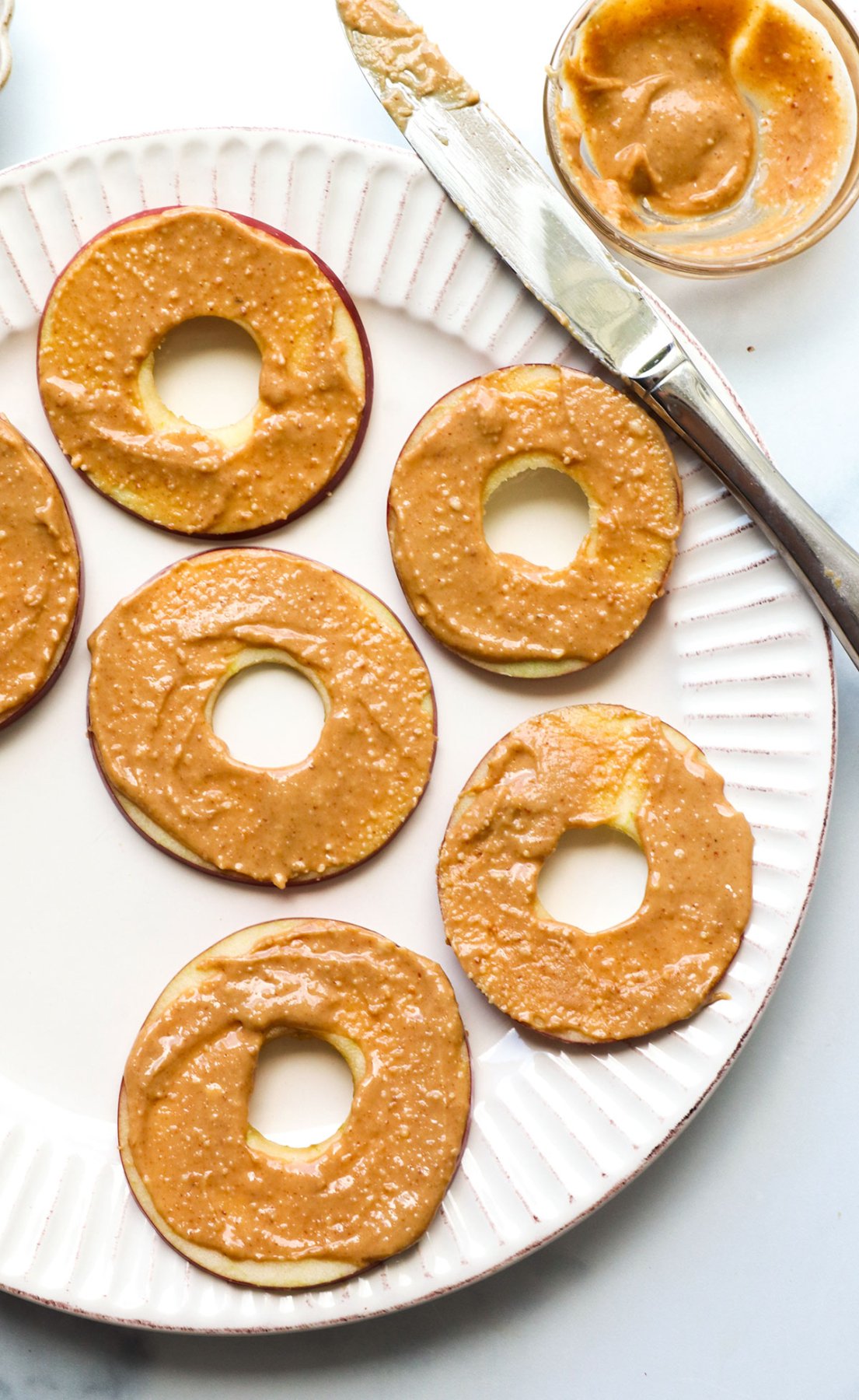 peanut butter spread thinly on apple slices that look like donuts.