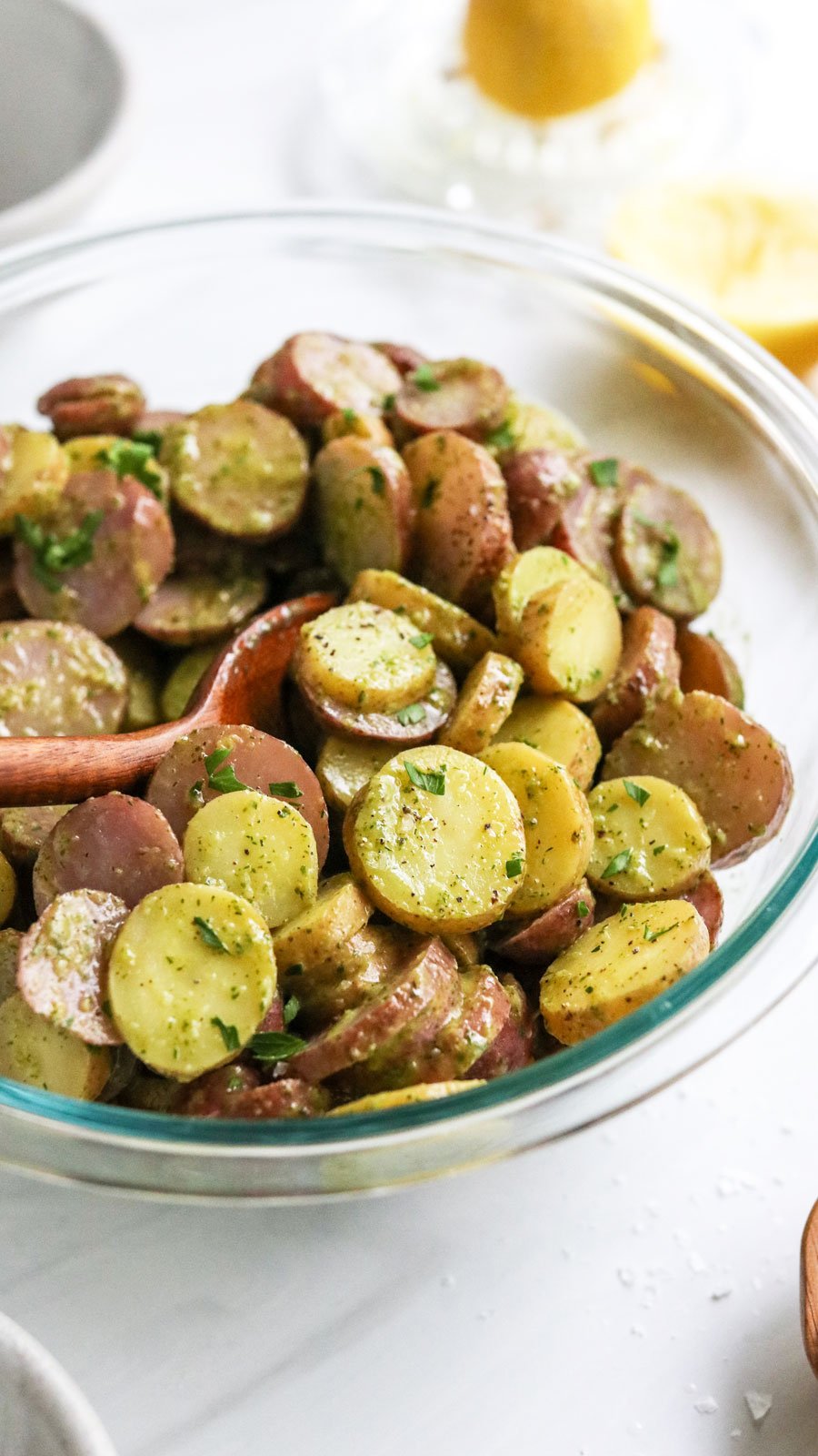 herbed potato salad stirred with wooden spoon.