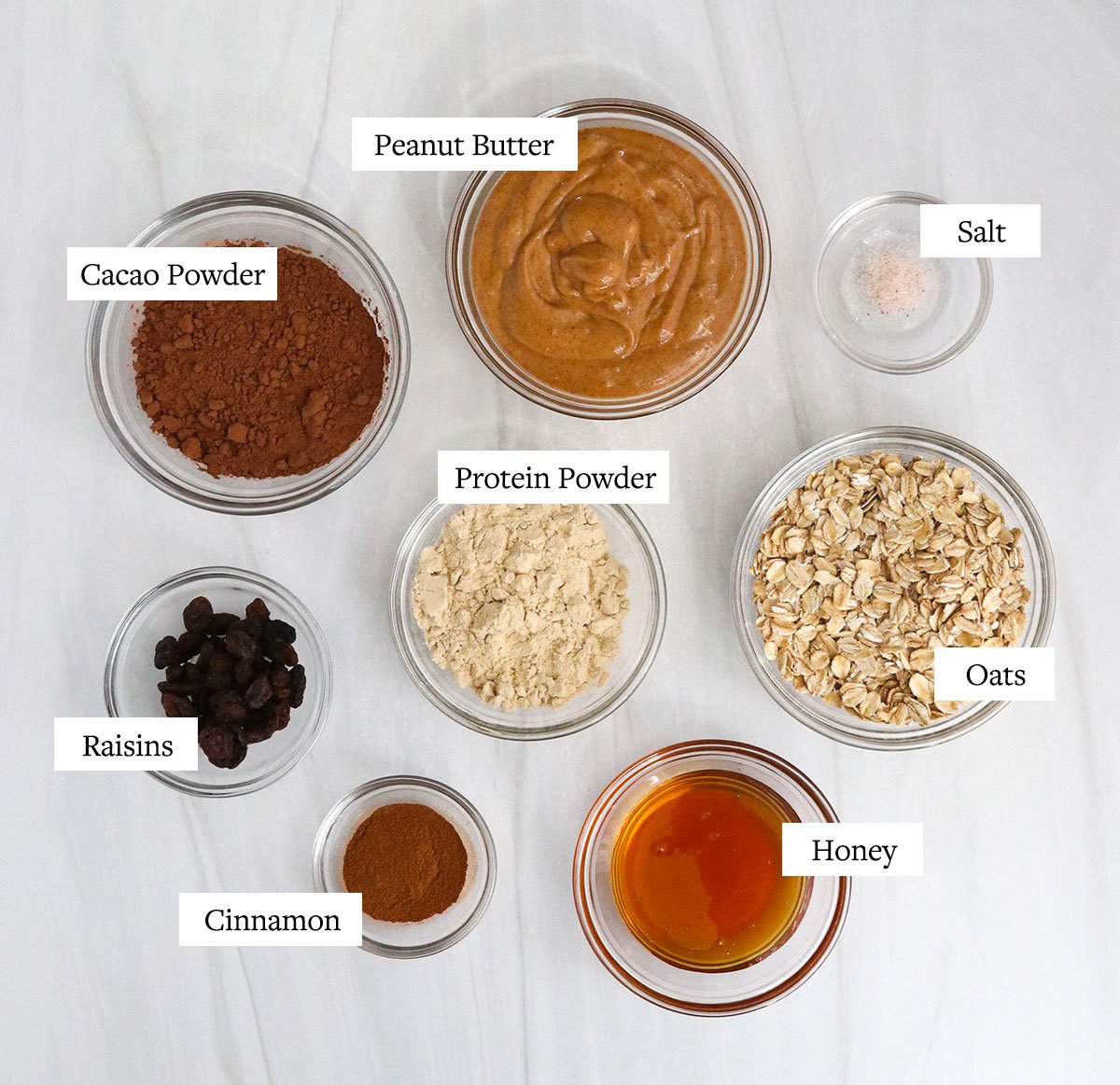 protein ball ingredients labeled in glass bowls.