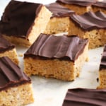 protein rice crispy square topped with a chocolate coating on parchment paper.